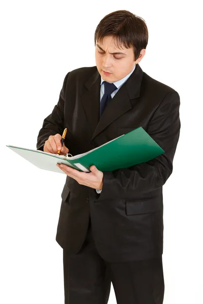 Serious young businessman holding folder in hand and making notes in docume — Stock Photo, Image