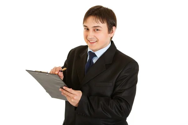 Χαμογελαστός νεαρός επιχειρηματίας κάνει τις σημειώσεις στο έγγραφο — Φωτογραφία Αρχείου