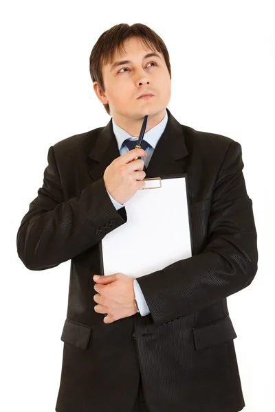 Pensive businessman with clipboard holding pen near his chin — Stock Photo, Image