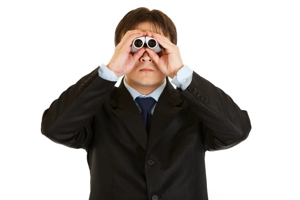 Jovem empresário sério olhando através de binóculos — Fotografia de Stock