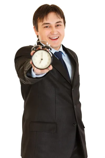 Smiling young businessman holding alarm clock in hand — Stock Photo, Image