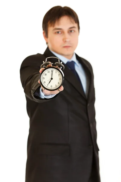 Serious young businessman holding alarm clock in hand — Stock Photo, Image