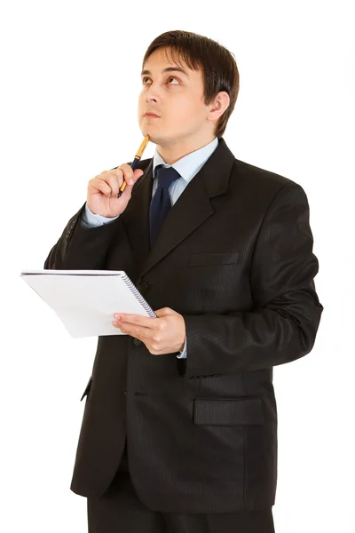 Задумчивый бизнесмен с блокнотом, держащим ручку у подбородка — стоковое фото