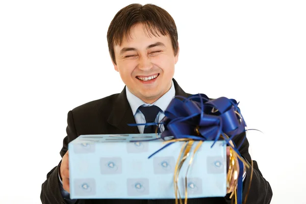Laughing young businessman holding gift in hands — Stock Photo, Image