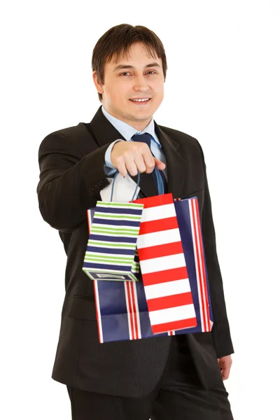 stock image Smiling young businessman giving shopping bags