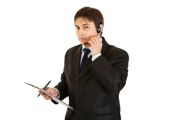 Serious young businessman with headset and clipboard — Stock Photo, Image