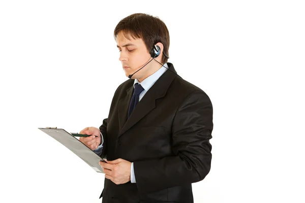 Seriöser Geschäftsmann mit Headset, der Notizen im Dokument prüft — Stockfoto