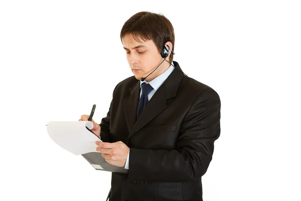 Joven empresario serio con auriculares y anotaciones en documento — Foto de Stock