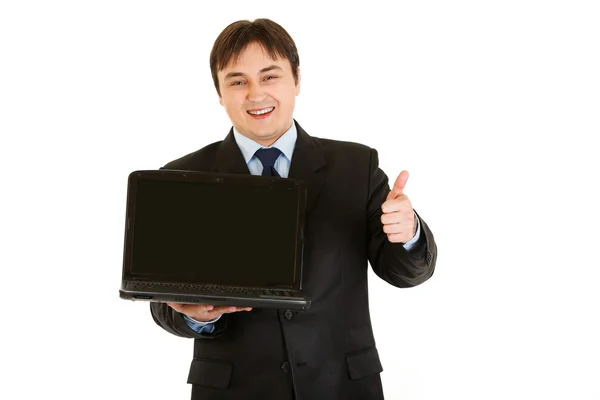 Sorridente uomo d'affari moderno in possesso di computer portatili schermo vuoto e mostrando pollici — Foto Stock