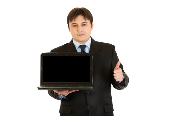 微笑商人持有笔记本电脑空白屏幕，并显示 ge 竖起大拇指 — 图库照片