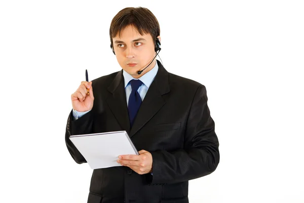 Fundersam affärsman med headsetet håller notebook i hand — Stockfoto