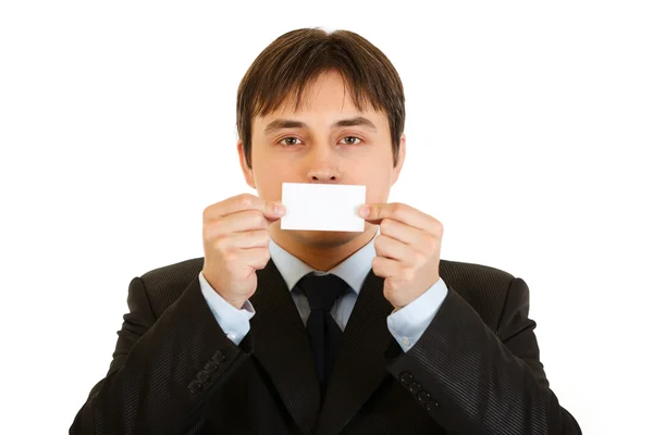 Modern businessman holding blank business card in front of mouth — Stock Photo, Image