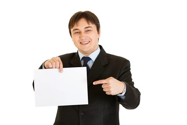 Улыбающийся современный бизнесмен указывает пальцем на пустую белую бумагу — стоковое фото