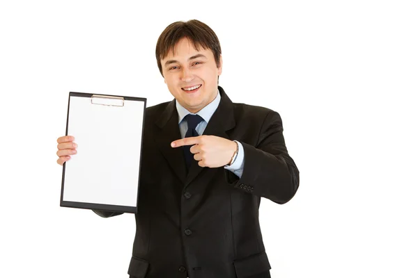 Smiling modern businessman pointing finger at blank clipboard — Stock Photo, Image