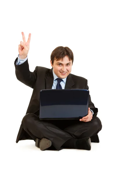 Dizüstü bilgisayarlar ile katta oturan ve zafer gest gösteren gülümseyen iş adamı — Stok fotoğraf
