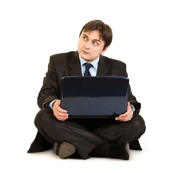 Задумчивый бизнесмен сидит с ноутбуком на полу и смотрит на копировальный спа — стоковое фото