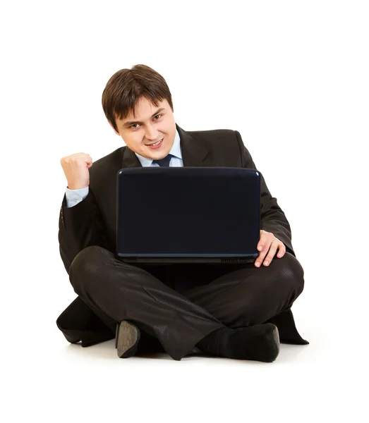Empresário moderno animado sentado no chão com laptop e regozijando seu s — Fotografia de Stock