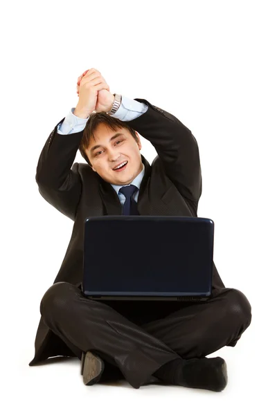 Улыбающийся бизнесмен, сидящий на полу с ноутбуками и показывающий партнерство — стоковое фото