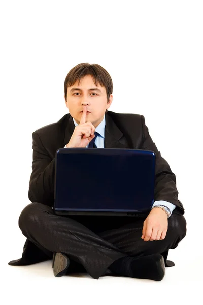 Sitting with laptop on floor businessman holding finger at mouth. Shh gestu — Stock Photo, Image