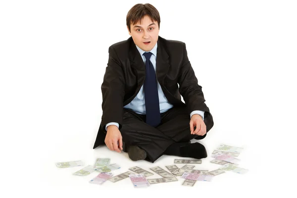 Välmående affärsman sitter på golvet omgiven av pengar — Stockfoto