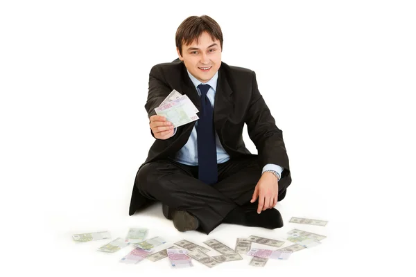 Exitoso hombre de negocios sentado en el suelo rodeado de dinero —  Fotos de Stock