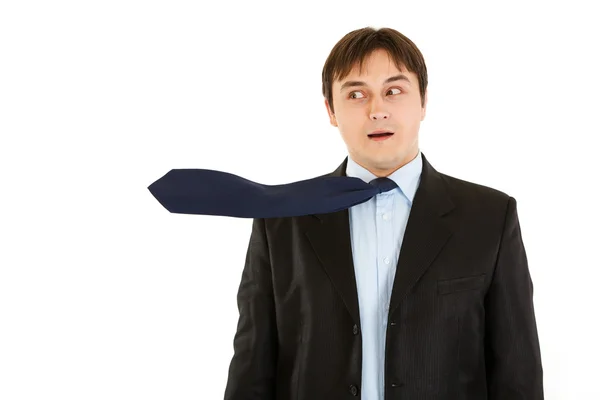 Překvapený mladý podnikatel s foukáním kravatový — Stock fotografie