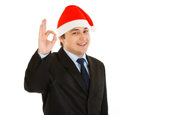 Šťastný mladý podnikatel v klobouku vánoční ukazující ok gesto. — Stock fotografie