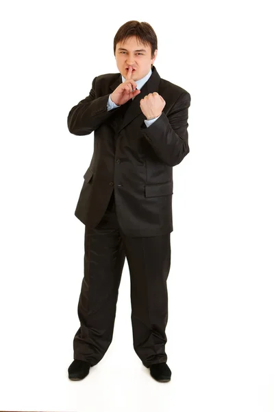 Злой бизнесмен с пальцем в рот и угрожает кулаком — стоковое фото