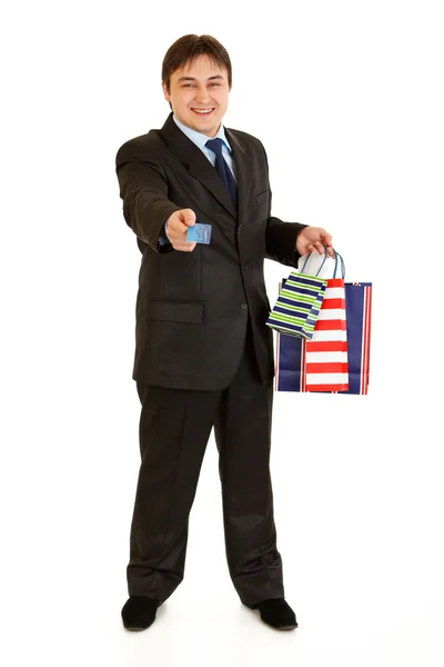 Full length portrait of smiling young businessman with shopping bags giving — Stock Photo, Image
