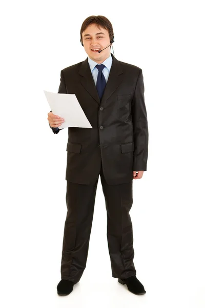 Smiling young businessman with headset holding document in hand — Stock Photo, Image