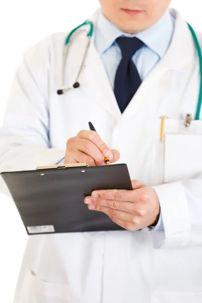 Medical doctor with stethoscope making notes in document. Close-up. — Stock Photo, Image