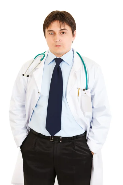 Серьезный врач со стетоскопом держит руки в карманах — стоковое фото