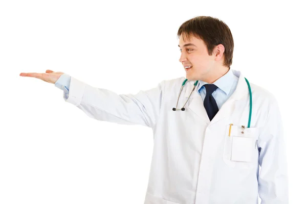 Médico sorridente apresentando algo na mão vazia — Fotografia de Stock