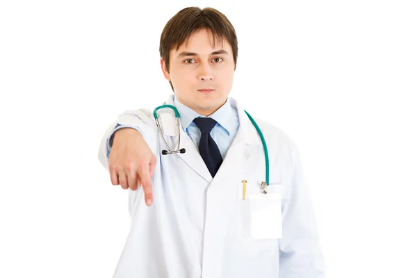 Ernsthafter junger Arzt zeigt mit dem Finger nach unten — Stockfoto