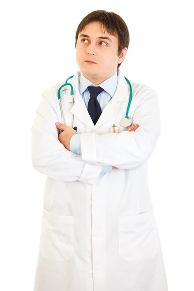 Médico reflexivo con brazos cruzados en el pecho mirando hacia arriba en el espacio de copia — Foto de Stock