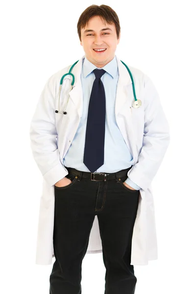 Улыбающийся доктор со стетоскопом держит руки в карманах — стоковое фото