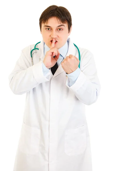Arg medicinsk läkare med fingret mot munnen och hota med knytnäve — Stockfoto