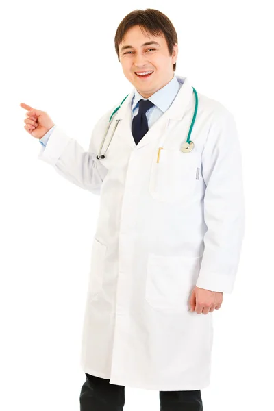 Médico sorridente apontando o dedo para algo — Fotografia de Stock
