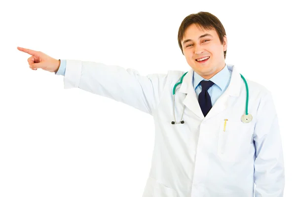 Улыбающийся доктор, указывающий пальцем в угол на пространство для копирования — стоковое фото