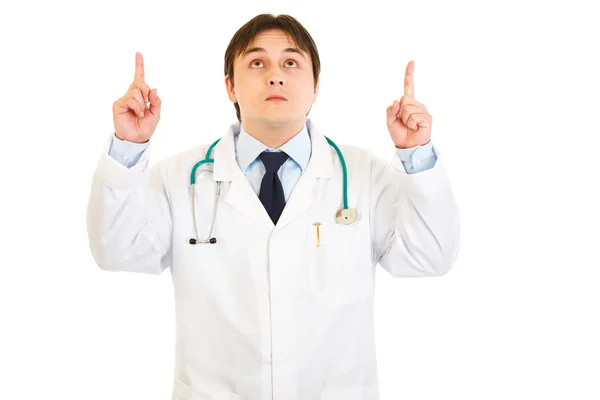Sorrindo jovem médico apontando os dedos para cima — Fotografia de Stock