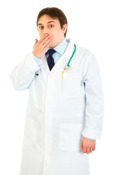 Shocked young medical doctor holding hand near mouth — Stock Photo, Image