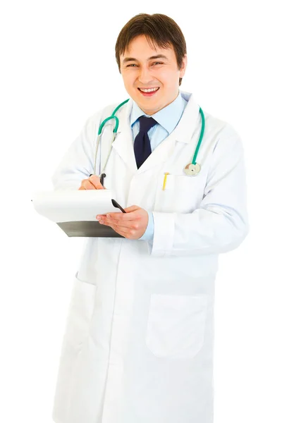 Médico sorridente com estetoscópio fazendo anotações em documento — Fotografia de Stock
