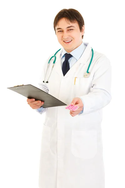 Smiling doctor holding clipboard and prescription drugs in hands — Stock Photo, Image