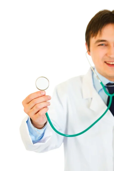 Jeune médecin souriant tenant le stéthoscope. Gros plan . — Photo