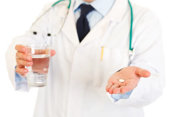 Medical doctor with pill and glass of water in hands. Close-up. — Stock Photo, Image
