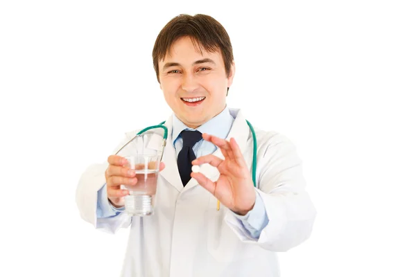 Médico sorridente com comprimido e copo de água nas mãos — Fotografia de Stock