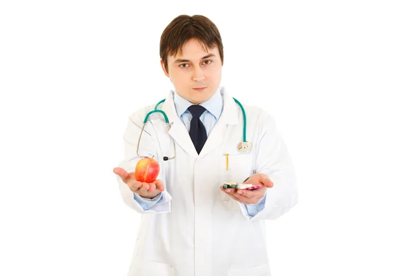 Уверенный врач с таблетками в одной руке и яблоком в другой — стоковое фото
