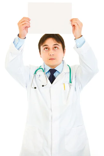 Médico sosteniendo papel blanco sobre la cabeza y mirándolo —  Fotos de Stock
