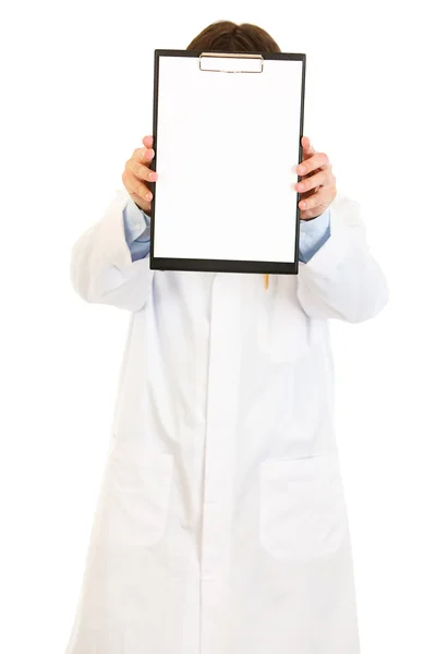 Médico segurando prancheta em branco na frente de seu rosto — Fotografia de Stock
