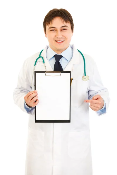 Smiling medical doctor pointing finger at blank clipboard — Stock Photo, Image